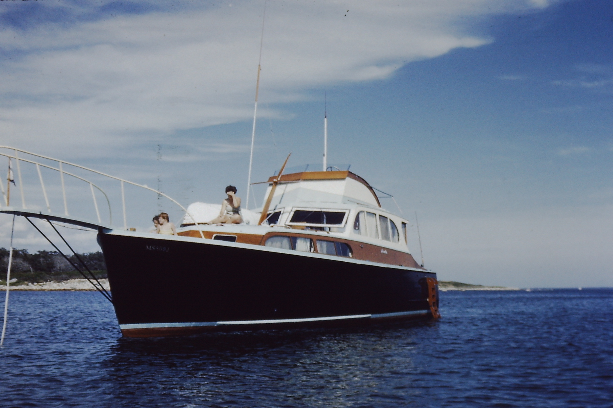Classic powerboat on calm water with family on deck